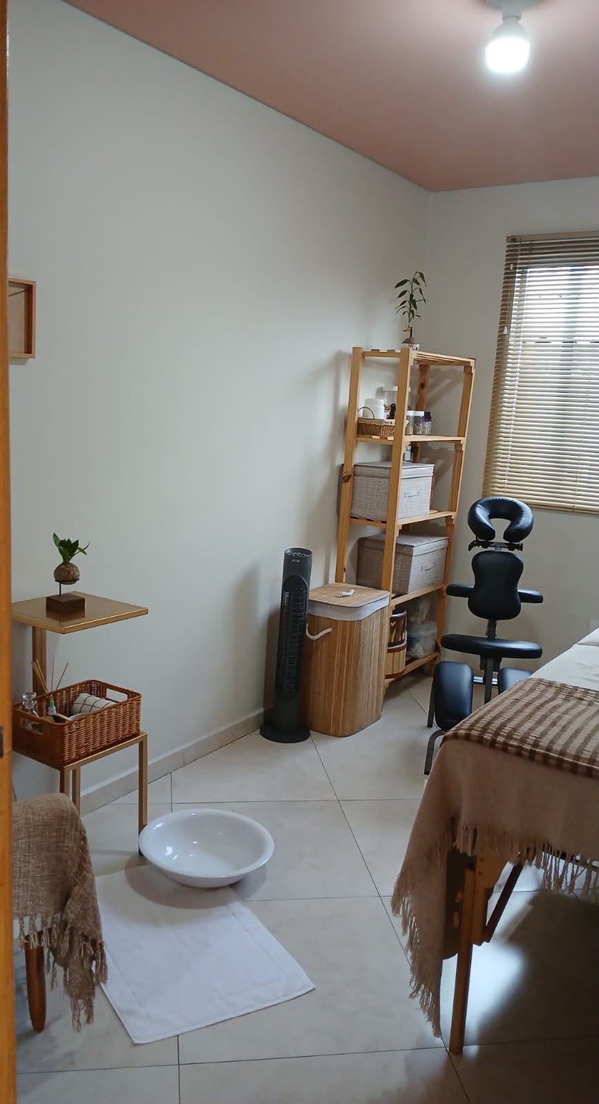 Ambiente aconchegante do studio com maca e cadeira de massagem